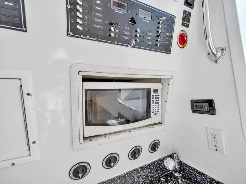 Slide: The Image of Built-in microwave and control panel on a 2015 SeaHunter 45 boat. - 16