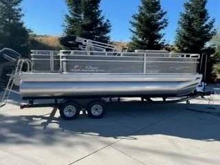 The Image of 2024 Sun Tracker Fishin' Barge 20 DLX pontoon boat on a trailer. - 0