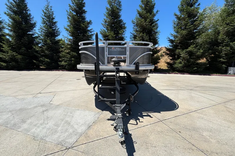 Slide: The Image of 2024 Sun Tracker Fishin' Barge 20 DLX pontoon boat on trailer, surrounded by trees. - 6