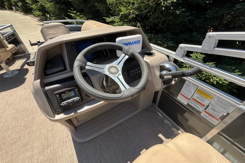 Slide: The Image of 2024 Sun Tracker Fishin' Barge 20 DLX helm with steering wheel and control panel. - 24