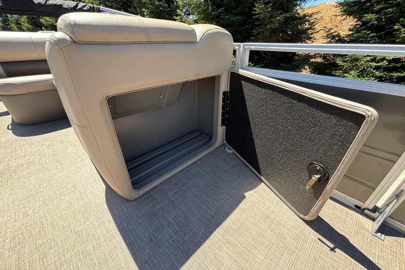 Slide: The Image of 2024 Sun Tracker Fishin' Barge 20 DLX storage compartment with open seat revealing interior space. - 38
