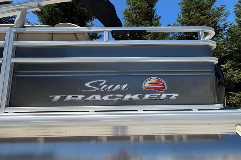 Slide: The Image of 2024 Sun Tracker Fishin' Barge 20 DLX pontoon boat with logo, surrounded by trees. - 14