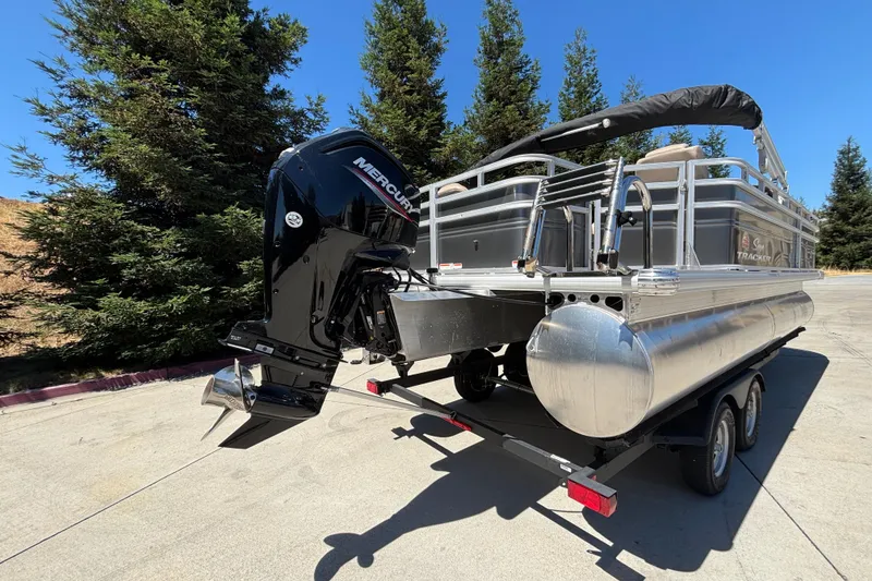 Slide: The Image of 2024 Sun Tracker Fishin' Barge 20 DLX pontoon boat on trailer, featuring Mercury outboard motor. - 7