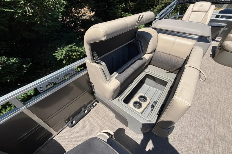 Slide: The Image of 2024 Sun Tracker Fishin' Barge 20 DLX interior with open storage compartment and cup holders. - 22