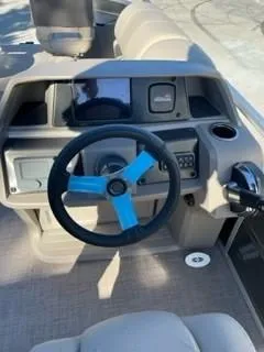 Slide: The Image of 2024 Sun Tracker Fishin' Barge 20 DLX steering console with blue-accented wheel. - 8