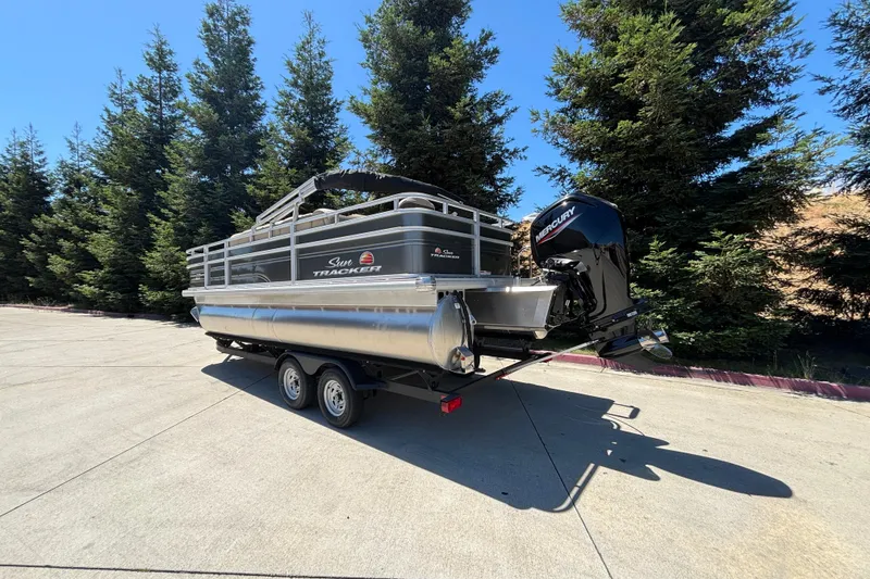 Slide: The Image of 2024 Sun Tracker Fishin' Barge 20 DLX pontoon boat on trailer, parked outdoors. - 3