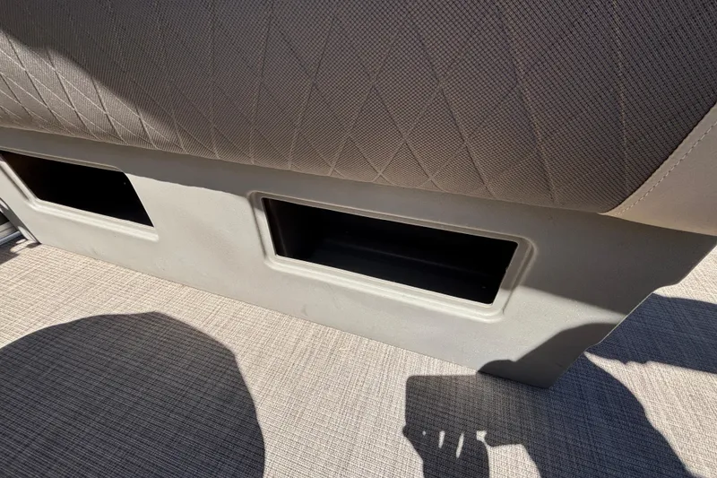 Slide: The Image of 2024 Sun Tracker Fishin' Barge 20 DLX seat storage compartments, beige upholstery, and textured flooring. - 46