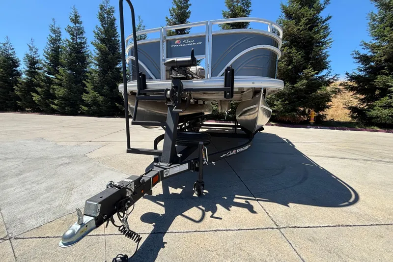 Slide: The Image of 2024 Sun Tracker Fishin' Barge 20 DLX pontoon boat on trailer, parked outdoors. - 9