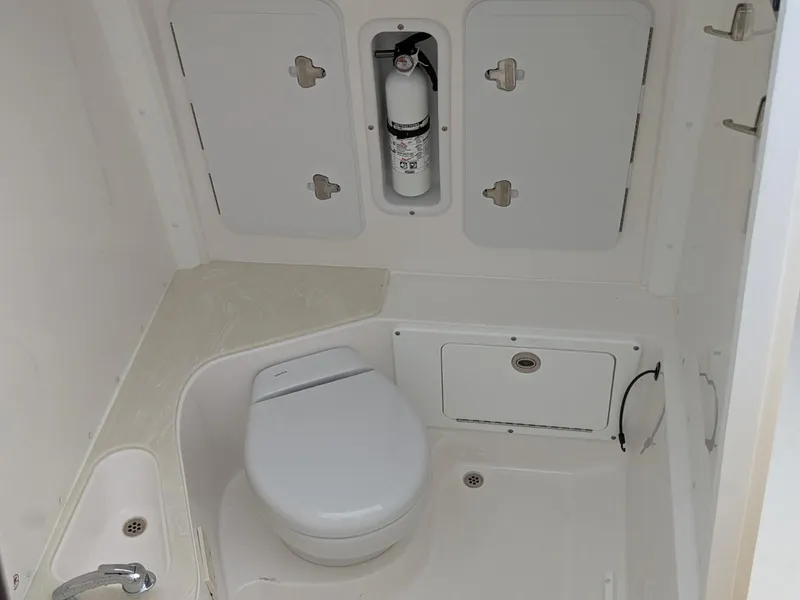 Slide: The Image of 2021 Edgewater 262 CC boat bathroom with toilet, sink, and storage compartments. - 16