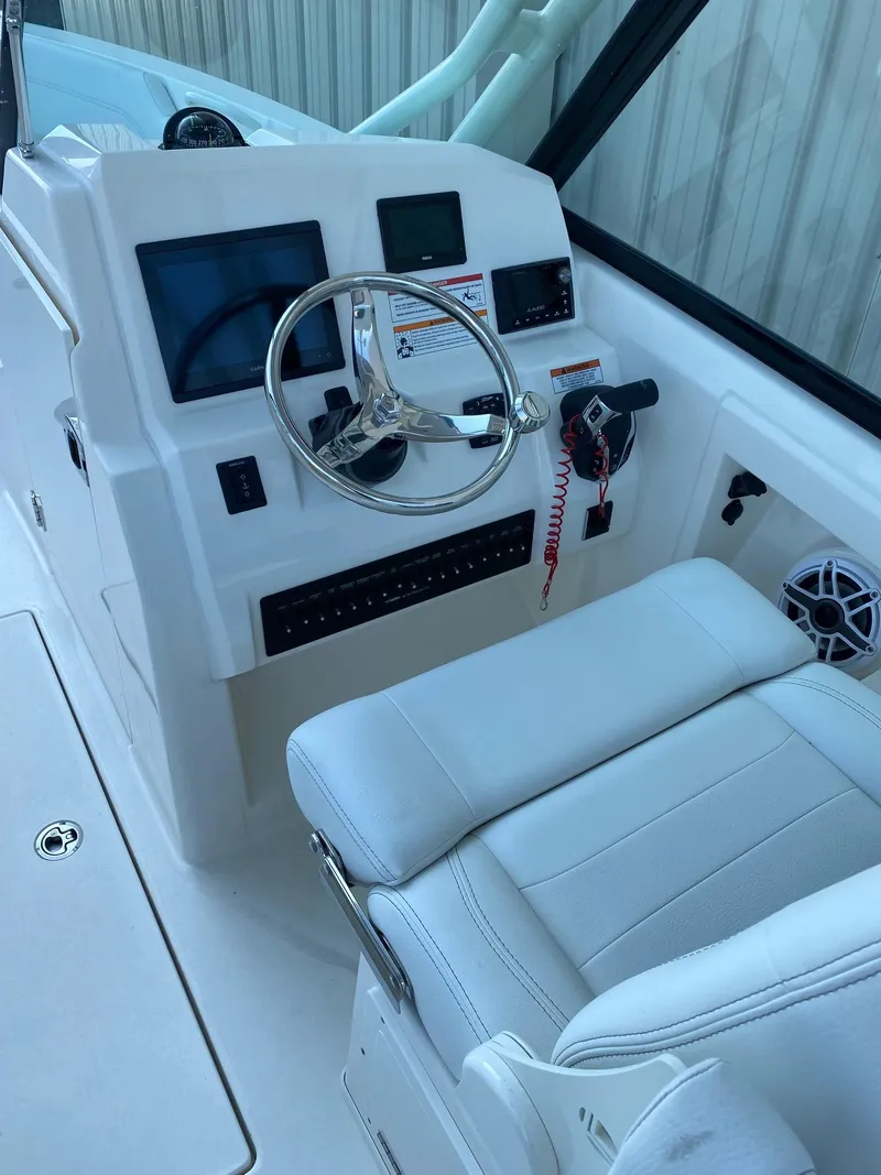 Slide: The Image of 2023 Cobia 240DC boat helm with modern controls and comfortable seating. - 2