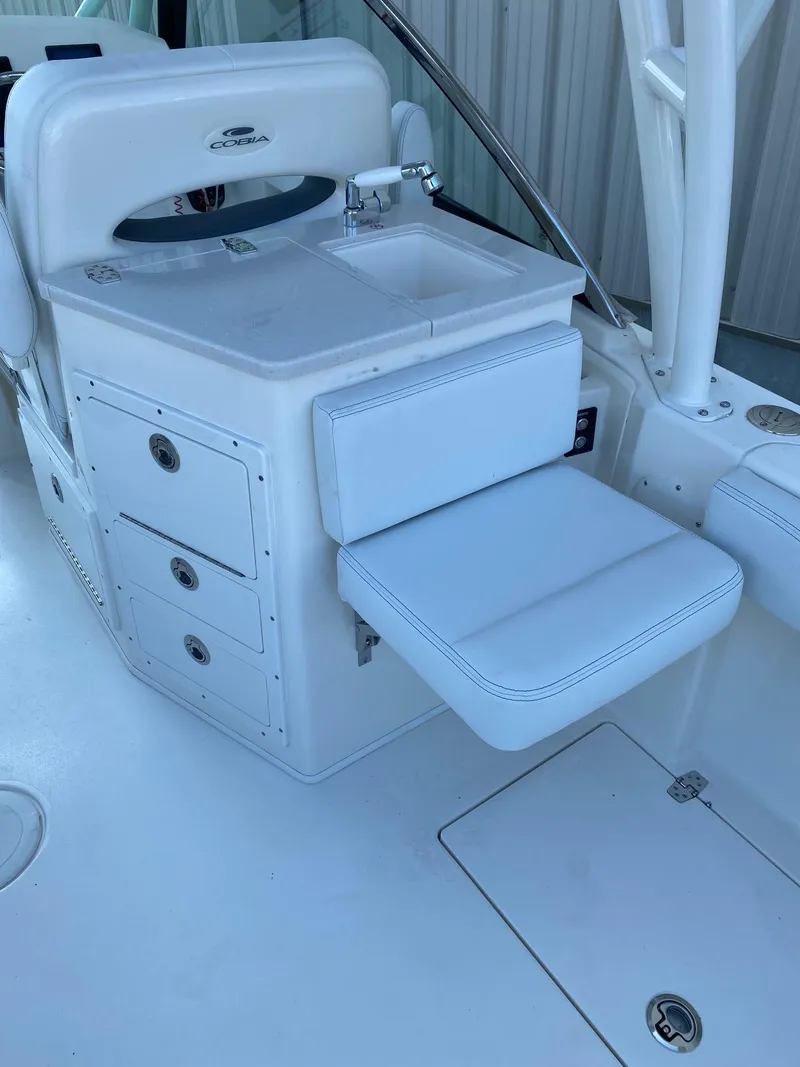 Slide: The Image of 2023 Cobia 240DC boat interior with sink, storage drawers, and cushioned seat. - 5