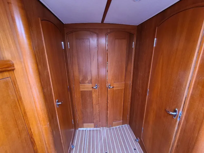 Slide: The Image of Wooden interior of 2004 Hunter 466 yacht with multiple doors and striped flooring. - 21