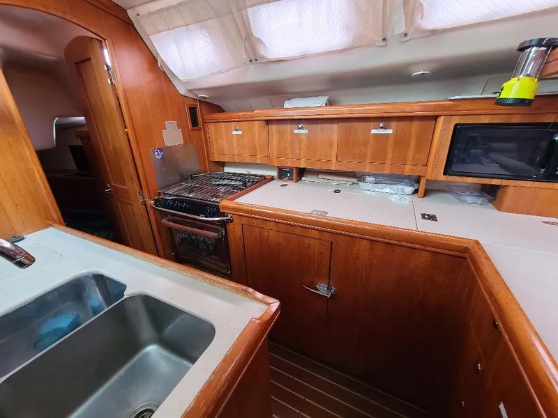 Slide: The Image of 2004 Hunter 466 yacht kitchen with wooden cabinetry, stove, sink, and microwave. - 26