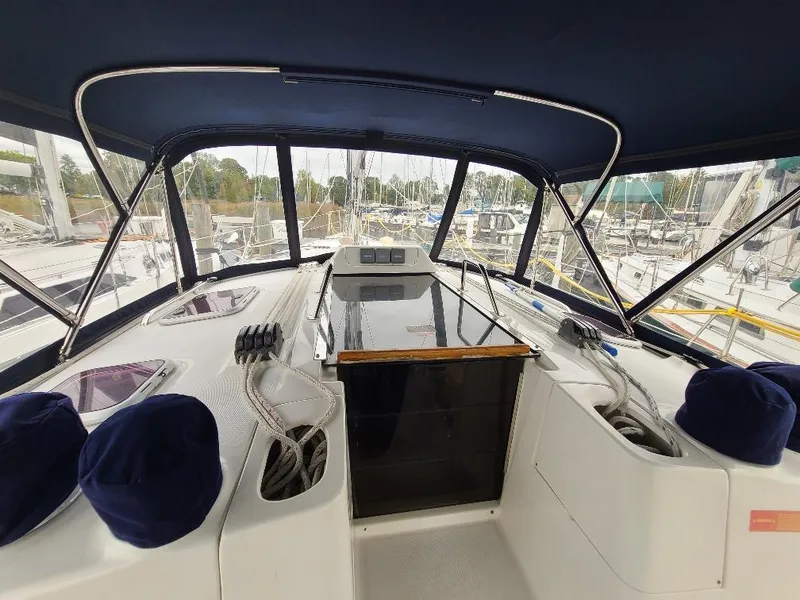 Slide: The Image of Interior view of 2004 Hunter 466 sailboat cockpit with blue canopy and marina background. - 6