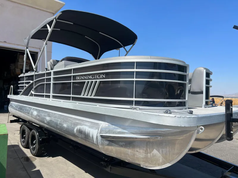 The Image of 2022 Bennington 23 L pontoon boat with black canopy on trailer. - 1