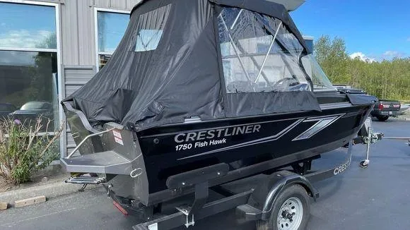 Slide: The Image of 2023 Crestliner 1750 Fish Hawk boat with black cover on trailer. - 2