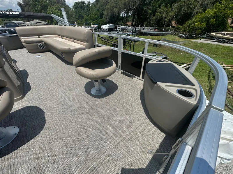 Slide: The Image of 2024 Ranger Reata 200F pontoon boat interior with beige seating and carpeted deck. - 11
