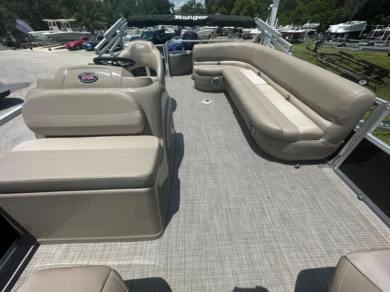 Slide: The Image of 2024 Ranger Reata 200F pontoon boat interior with beige seating and carpeted floor. - 3