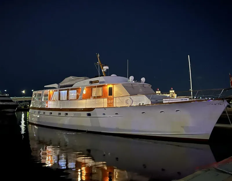 Slide: The Image of 1972 Trumpy 72 Houseboat illuminated at night, docked in a marina. - 0