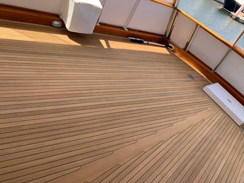 Slide: The Image of Teak deck of 1972 Trumpy 72 Houseboat with wooden railings and marina view. - 11