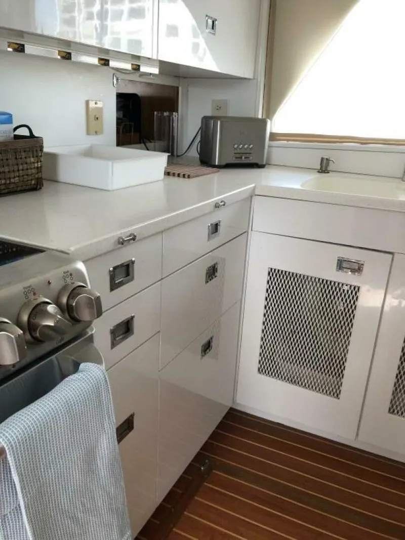 Slide: The Image of 1972 Trumpy 72 Houseboat kitchen with white cabinets, stainless steel appliances, and wooden flooring. - 19