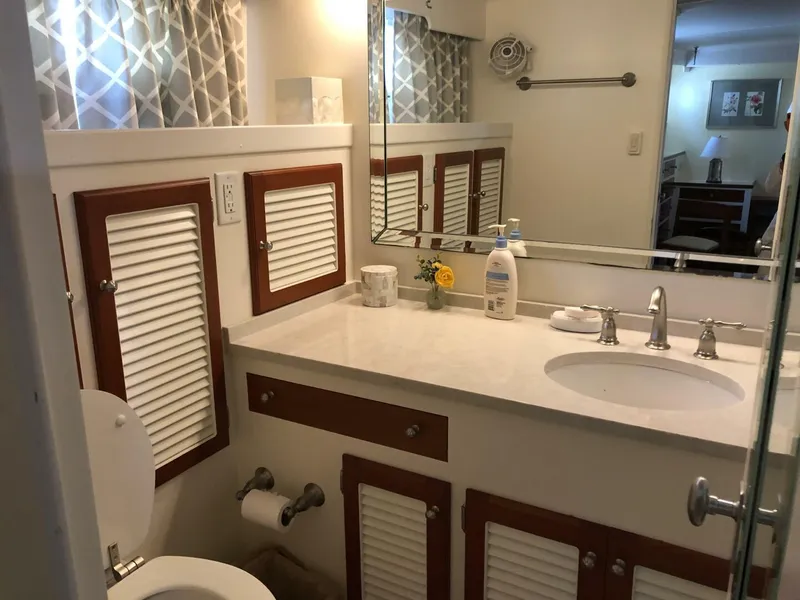 Slide: The Image of 1972 Trumpy 72 Houseboat bathroom with sink, mirror, and storage cabinets. - 26