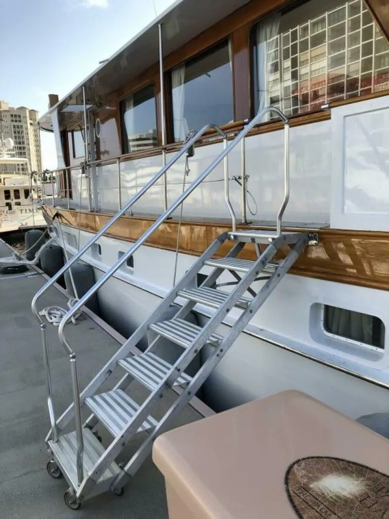 Slide: The Image of 1972 Trumpy 72 Houseboat with metal boarding stairs at dock. - 8