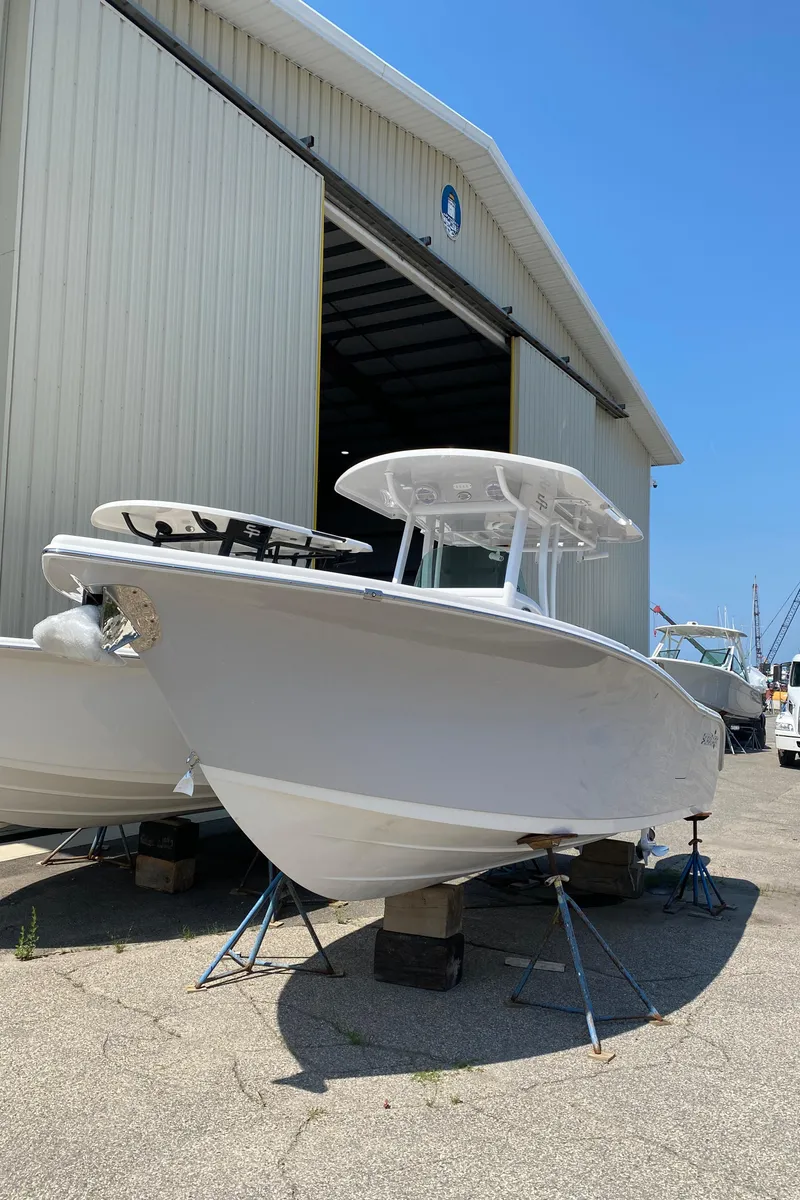 Slide: The Image of 2023 Sea Pro 259 boat outside a large storage building. - 2