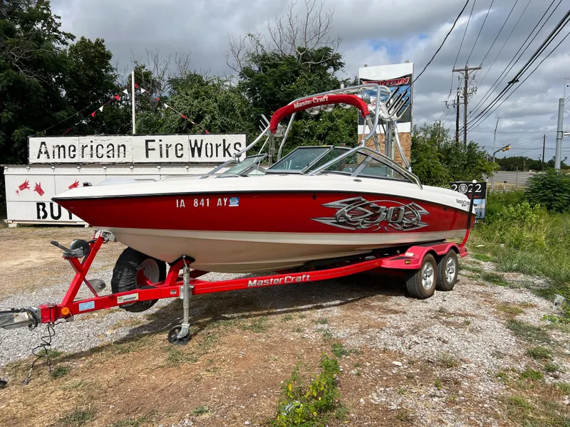 Slide: The Image of 2004 MasterCraft X30 boat on a red trailer near American Fireworks store. - 1