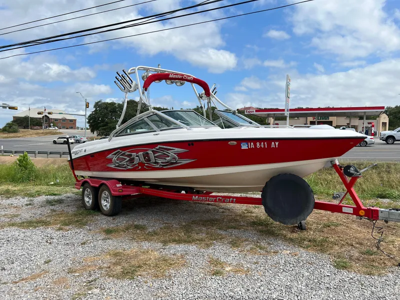 Slide: The Image of 2004 MasterCraft X30 red and white boat on a trailer in a parking lot. - 2