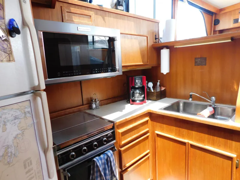 Slide: The Image of 1988 Chris-Craft 426 Catalina kitchen with wood cabinetry, microwave, stove, and sink. - 19
