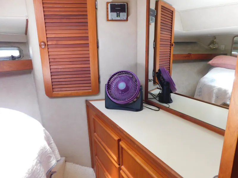 Slide: The Image of 1988 Chris-Craft 426 Catalina cabin interior with wooden cabinets and a purple fan. - 23