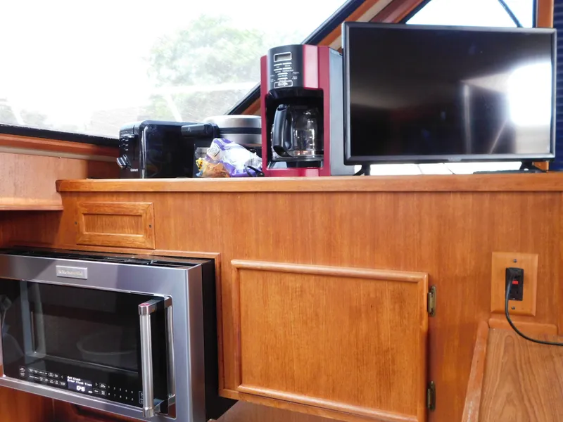 Slide: The Image of 1988 Chris-Craft 426 Catalina interior with microwave, coffee maker, and TV on wooden cabinetry. - 48