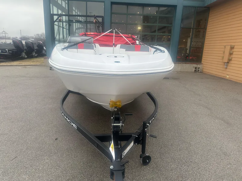 Slide: The Image of 2024 Tahoe T18 boat on trailer, parked outside a showroom. - 2