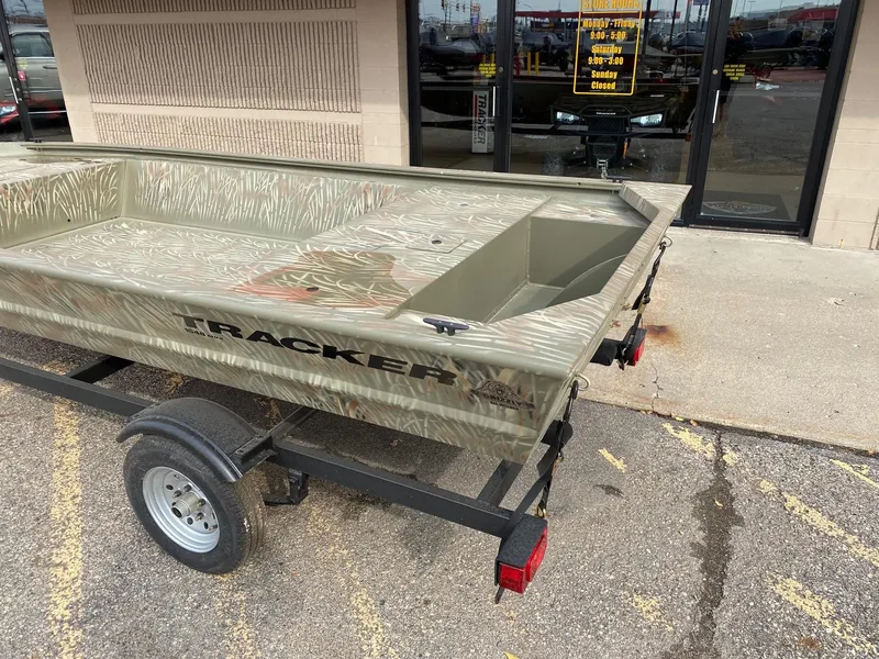 Slide: The Image of 2024 Tracker Grizzly 1648 Jon boat on a trailer outside a store. - 2