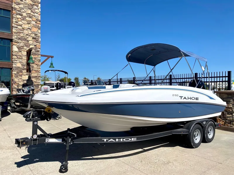 The Image of 2024 Tahoe 2150 boat on trailer with canopy, parked outdoors. - 0