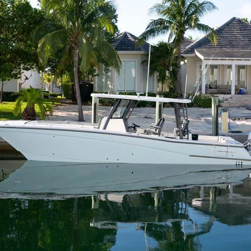 The Image of 2022 World Cat 400CC-X boat docked near a tropical waterfront home. - 1