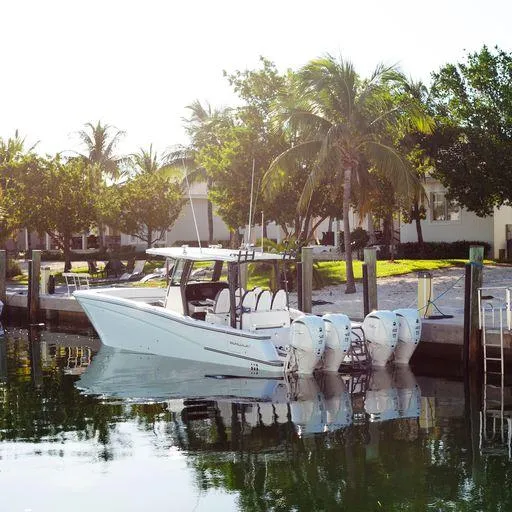 Slide: The Image of 2022 World Cat 400CC-X boat docked near palm trees. - 2