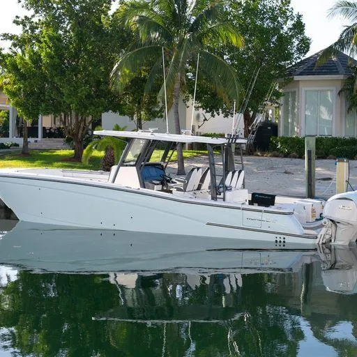 Slide: The Image of 2022 World Cat 400CC-X boat docked near a tropical waterfront home. - 3