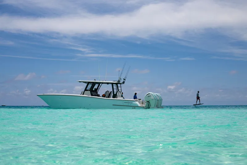 Slide: The Image of 2022 World Cat 400CC-X boat on clear turquoise water with a person paddleboarding nearby. - 4