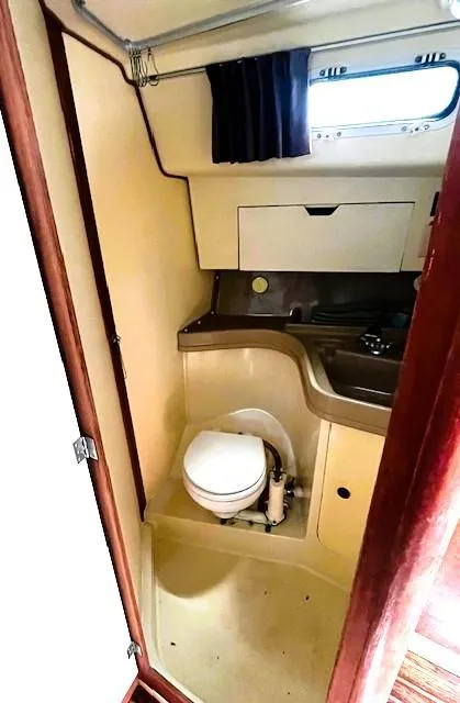 Slide: The Image of 1986 Pearson 303 yacht bathroom with toilet, sink, and storage cabinet. - 12