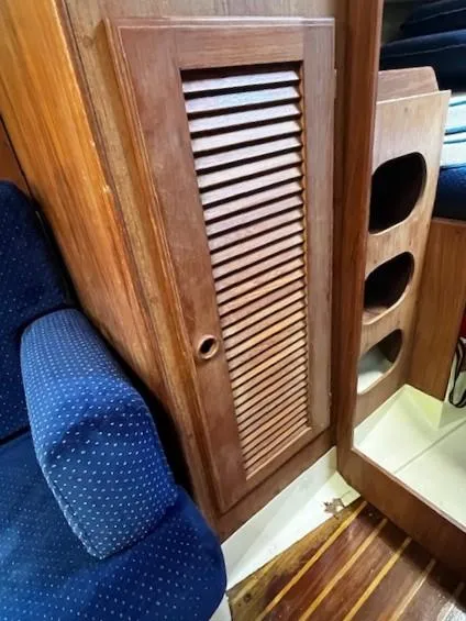 Slide: The Image of 1986 Pearson 303 interior with wooden louvered cabinet and blue upholstered seating. - 13