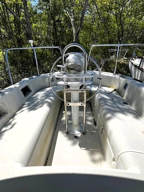 Slide: The Image of 1986 Pearson 303 sailboat cockpit with steering wheel, surrounded by lush greenery. - 17