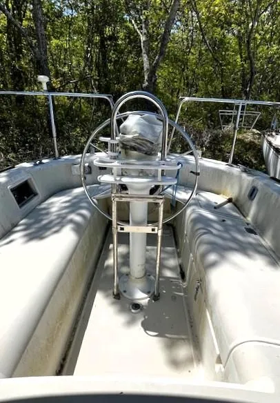 Slide: The Image of 1986 Pearson 303 sailboat cockpit with steering wheel, surrounded by lush greenery. - 2