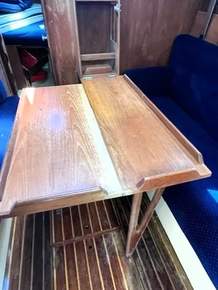 Slide: The Image of 1986 Pearson 303 sailboat interior with wooden table and blue seating. - 23