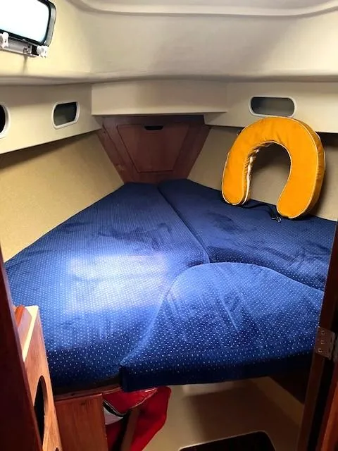 Slide: The Image of Cozy cabin interior of 1986 Pearson 303 sailboat with blue bedding and yellow neck pillow. - 25
