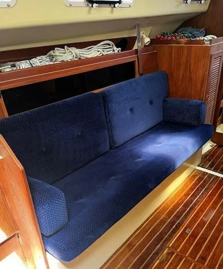 Slide: The Image of 1986 Pearson 303 yacht interior with blue cushioned seating and wooden flooring. - 29