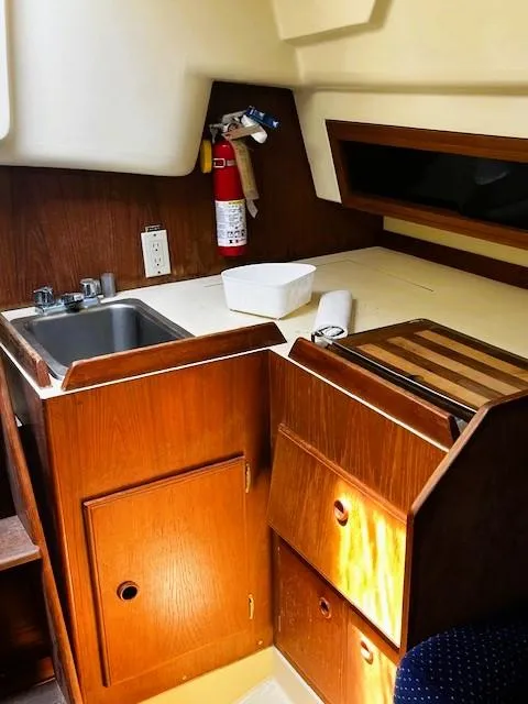 Slide: The Image of 1986 Pearson 303 yacht interior kitchen with wooden cabinets, sink, and fire extinguisher. - 33