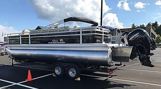 The Image of 2024 Sun Tracker Sportfish 24 XP3 pontoon boat on trailer in parking lot. - 0