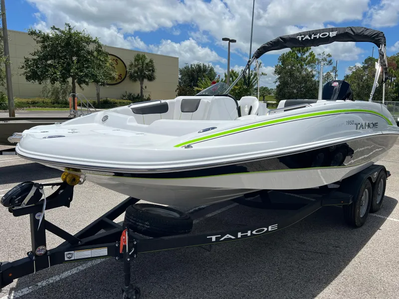 Slide: The Image of 2024 Tahoe 1950 boat on trailer in parking lot under blue sky. - 2